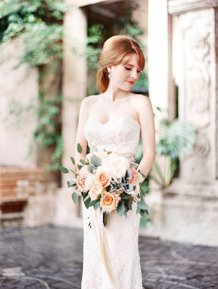 Allison's Bridals, Bride holding Rose floral arrangement looking over shoulder